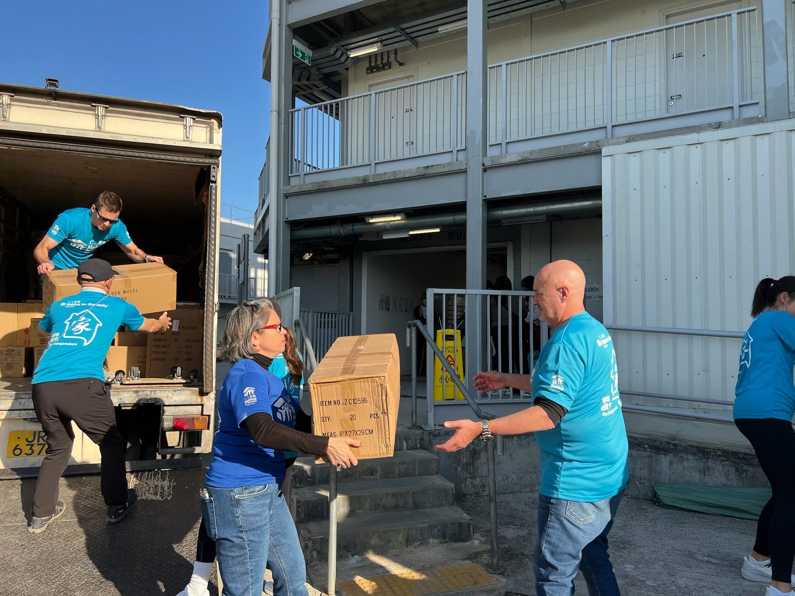 Volunteers unloading furniture and materials from a truck for a home project